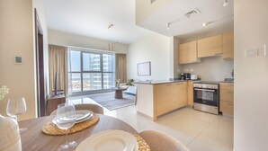A modern apartment with a dining area, kitchen, and large windows. - Bloomfields 1BR in Marina Bay 1  (Abu Dhabi)