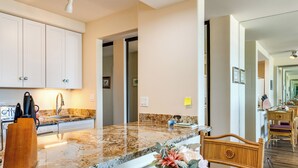 Eine moderne Küche mit Granit Arbeitsplatten, weißen Schränken und einem Holzstuhl.