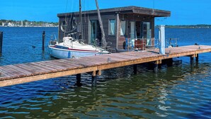 Un voilier amarré à un quai en bois, avec une petite construction à proximité.