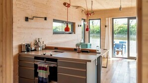 Une cuisine moderne dotée d’un îlot central, d’un plafond en bois et de grandes fenêtres.