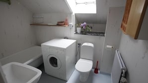 Ein kleines Badezimmer mit Waschmaschine, Toilette und Bidet.
