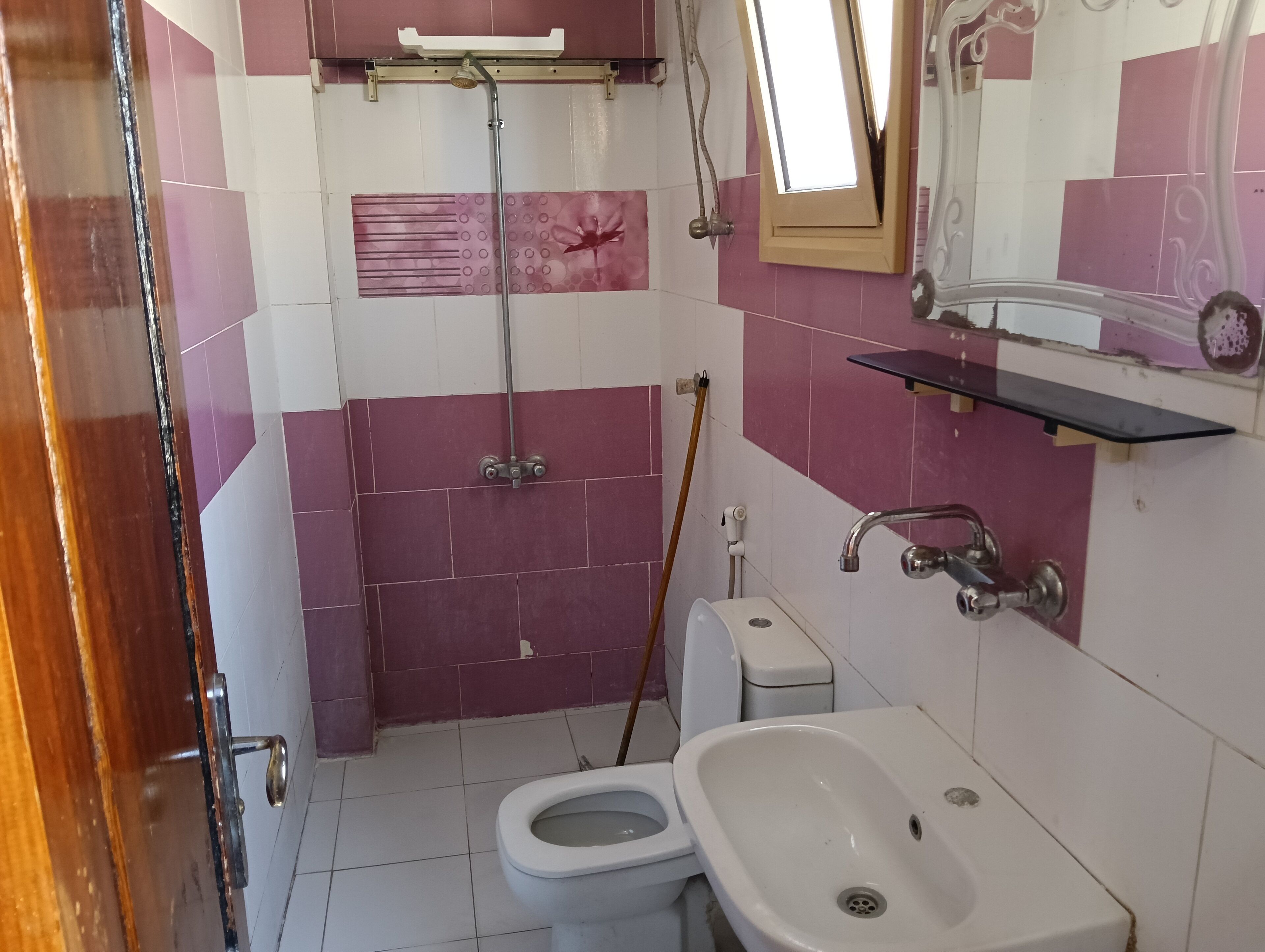A bathroom with a shower, toilet, sink, and a mirror.