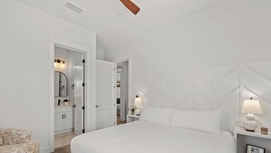 Een moderne hotelkamer met een groot bed, een nachtkastje met een lamp, een ingelijste foto en een gestreept fauteuil.