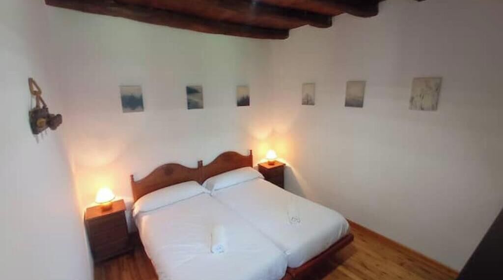 Un dormitorio con una cama de madera, dos mesitas de noche con lámparas y techo de madera.
