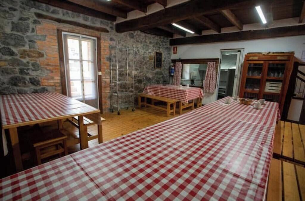 Una habitación rústica con paredes de piedra, mesas de madera con manteles a cuadros y un aparador de madera.