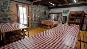 Una habitación rústica con paredes de piedra, mesas de madera con manteles a cuadros y un aparador de madera.