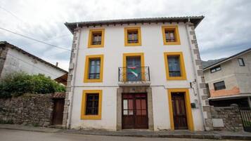 A two-story building with a balcony, a flag, and a stone wall.