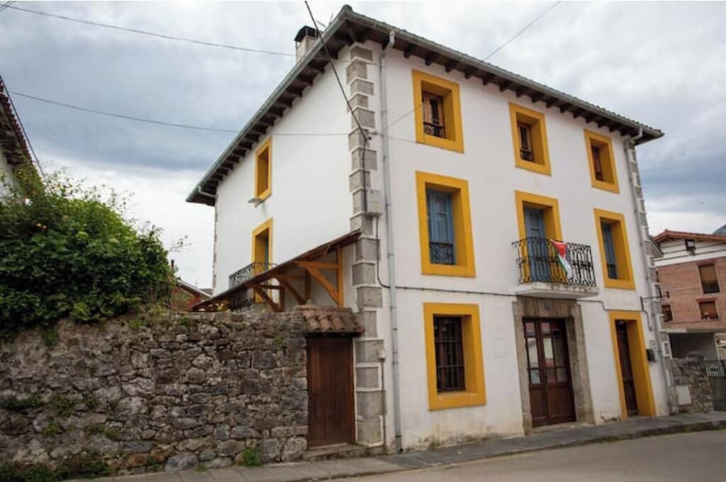 Un edificio de dos pisos con un muro de piedra y un balcón con barandilla.