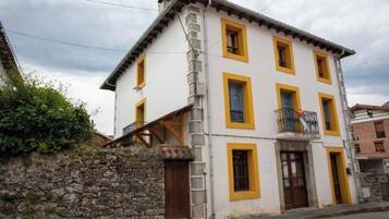 Un edificio de dos pisos con un muro de piedra y un balcón con barandilla.