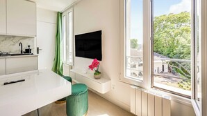 Eine moderne Küche mit Flachbildfernseher, einem grünen Sessel und einem Fenster mit Blick auf einen Baum und ein Gebäude.