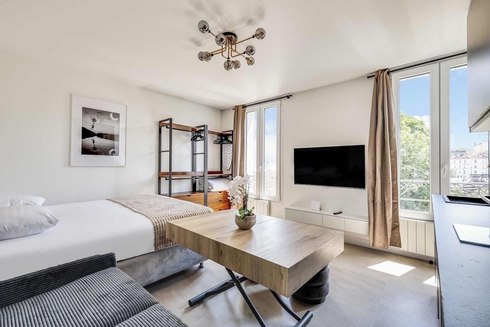 Ein modernes Hotelzimmer mit Bett, Schreibtisch, Fernseher und großen Fenstern.