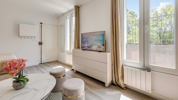 Een moderne kamer met een groot raam, een radiator, een schilderij en een klein tafeltje met een bloevas.