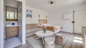 Een moderne slaapkamer met een bed, nachtkastje, rond bijzettafeltje en een spiegel.