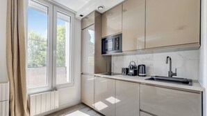 Een moderne keuken met een groot raam, een ingebouwde magnetron en een spoelbak.