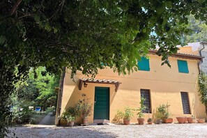 A building with a green door, multiple windows, and potted plants in front. - Peaceful Country Retreat near Pesaro (Pesaro)