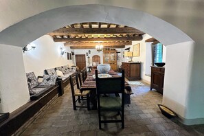 A dining area with a stone floor, wooden furniture, and an arched ceiling. - Peaceful Country Retreat near Pesaro (Pesaro)