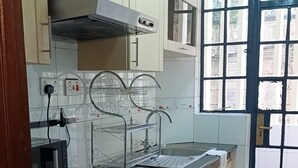 Una cocina con estufa a gas, horno y pileta. Se observa una ventana con vista al exterior.