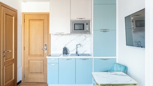 Eine kompakte Küche mit Mikrowelle, Spüle und einem kleinen Tisch.