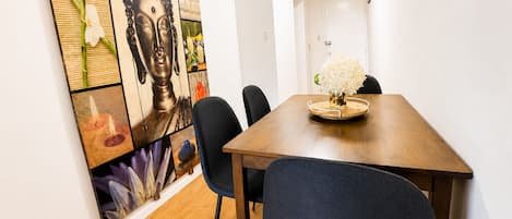 A dining area with a wooden table, black chairs, and a Buddha painting on the wall.