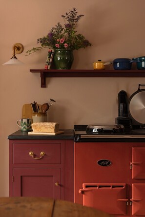 A kitchen with a red refrigerator, a coffee maker, a toaster, and a shelf with a vase of flowers and books. - Moy Cottage - sleeps 10, 5 bedrooms, pet-friendly Highland retreat (Moy)