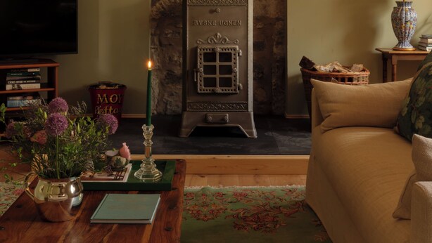 A cozy living room with a stone fireplace, a sofa, a coffee table, and two mounted antler decorations. - Cosy, newly renovated five bedroom cottage in the Highlands. Pet friendly! (Moy)