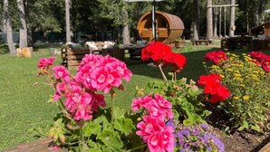 En trädgård med blommor, en trätrumma och ett bord under ett parasoll.