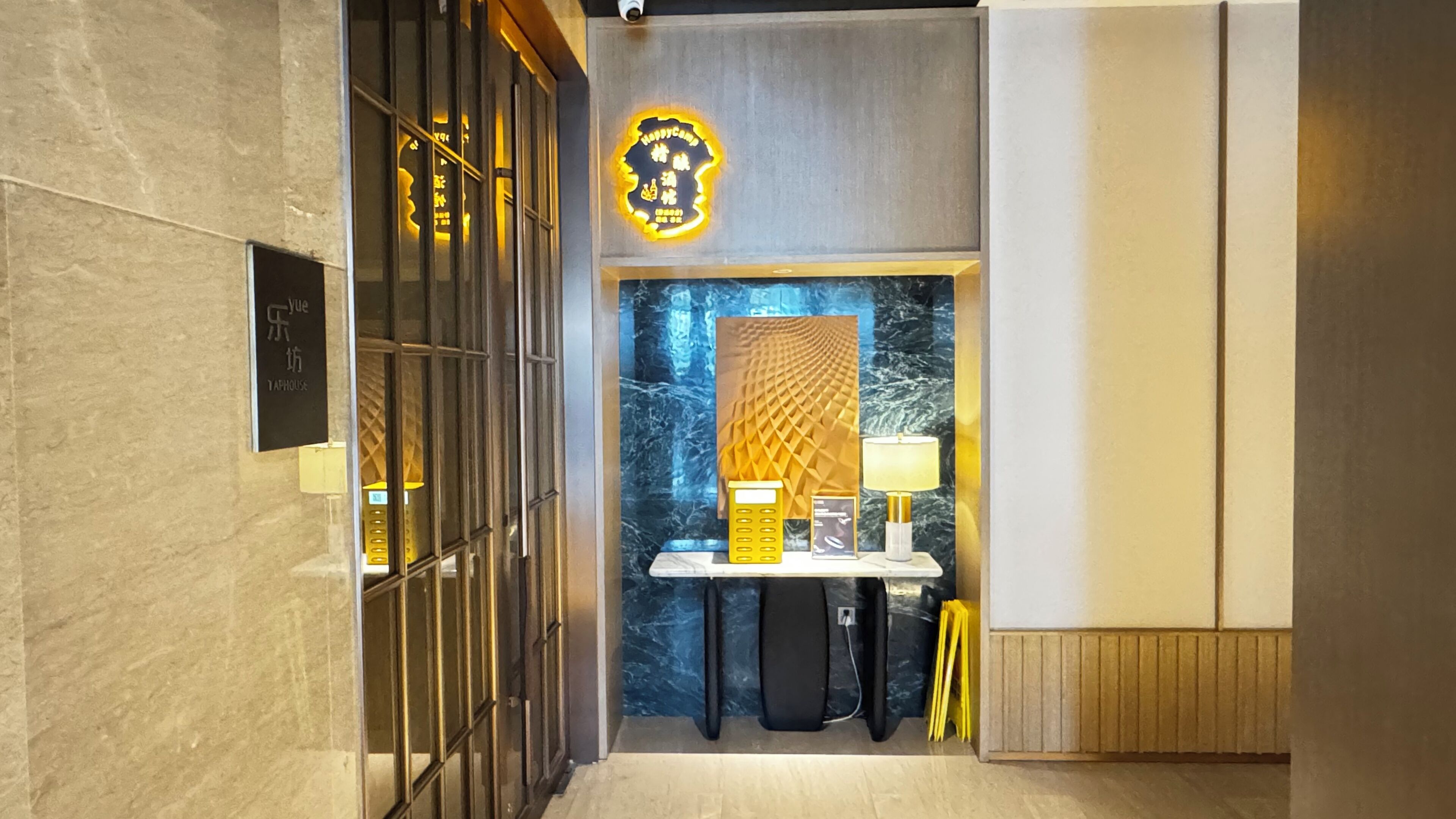 A hotel lobby with a reception desk, a decorative wall with a geometric pattern, and a sign with Chinese characters.