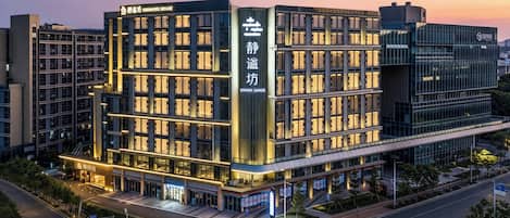 A multi-story hotel with a modern facade, illuminated signage, and a well-lit entrance.