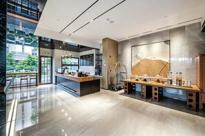 Un moderno vestíbulo de hotel con un mostrador de recepción, una estación de café y un amplio ventanal con vistas al exterior.