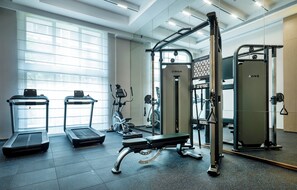 Un gimnasio con cintas de correr, bancos y máquinas de pesas.