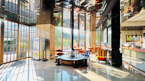 Un hall espacioso con grandes ventanales, una zona de estar central y un diseño moderno.