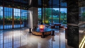 Un lobby moderno con chimenea central, ventanas amplias y piso pulido.