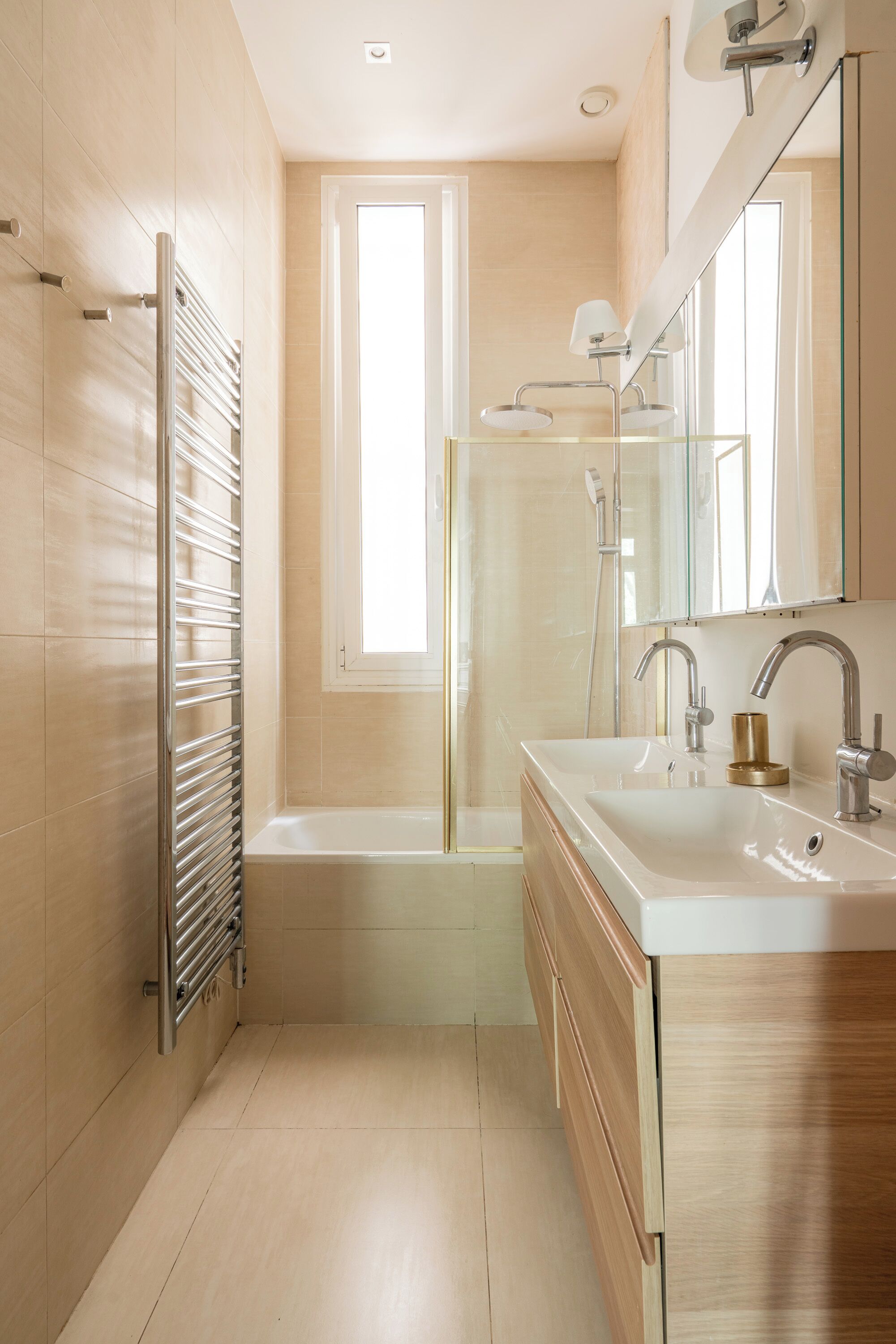 Un baño moderno con cabina de ducha de vidrio, una bañera, un espejo grande y un perchero para toallas.