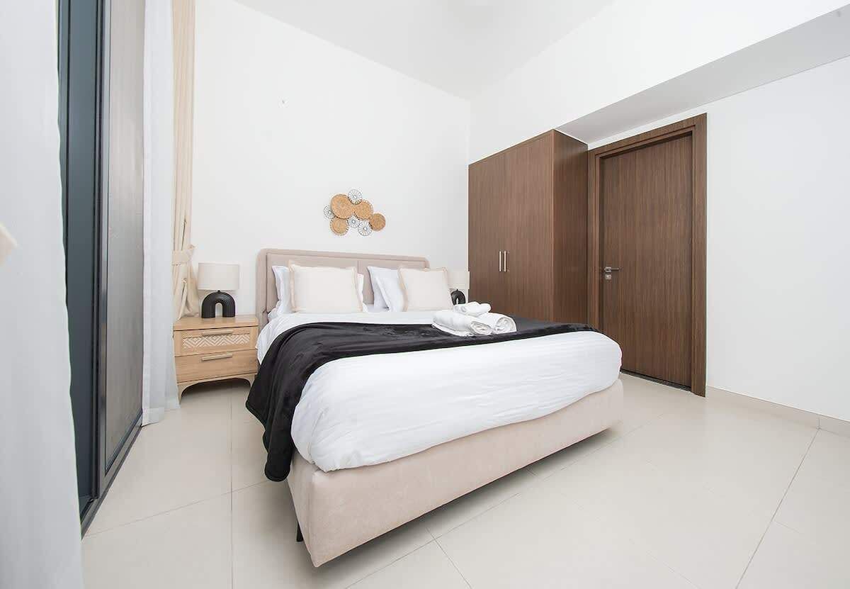 Een slaapkamer met een bed, nachtkastje en kledingkast.