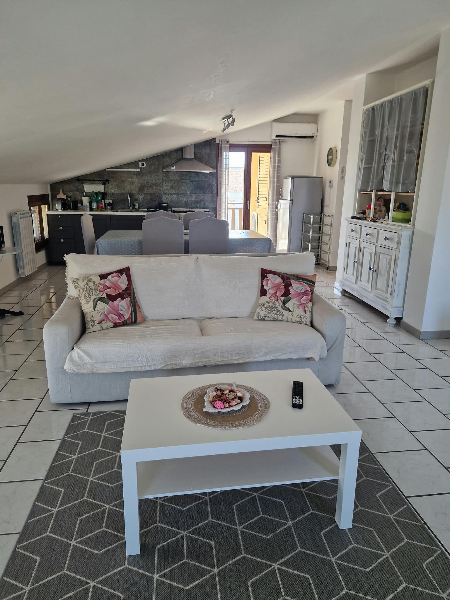 En stue med sofa, sofabord og et køkken i baggrunden.