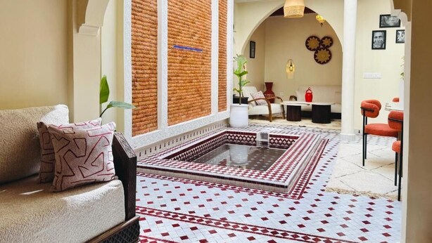Um interior acolhedor com piso estampado, um sofá com almofadas padronizadas e uma parede de tijolos.