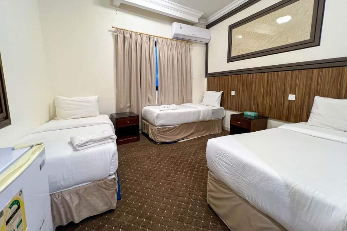 Ein Hotelzimmer mit zwei Betten, einem großen Spiegel, einer Klimaanlage und einem Vorhangfenster.