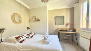 Ein Hotelzimmer mit Bett, Schreibtisch, Stuhl, Lampe und einem großen Fenster.