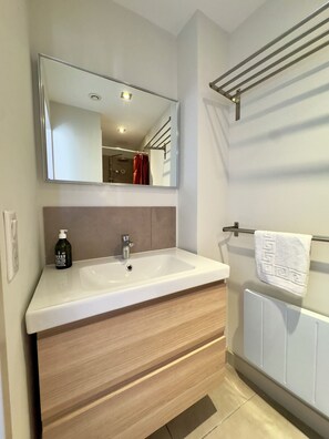 A modern bathroom with a white sink, a large mirror, a towel rack, and a bottle of soap. - L'Ajax, 2-bedroom apartment in the city center and by the sea (Ajaccio)