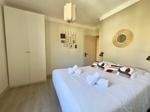 A bedroom with a bed, a wardrobe, a wall-mounted mirror, and framed pictures. - L'Ajax, 2-bedroom apartment in the city center and by the sea (Ajaccio)