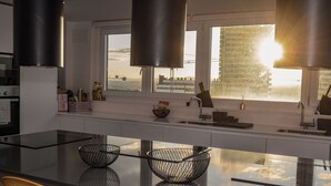 A modern kitchen with a large island, stainless steel appliances, and a view of the city skyline.