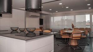 A modern kitchen with a central island, dining area with round table and chairs, and large windows with a city view.