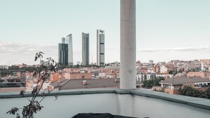 A balcony with a view of a cityscape, including modern buildings and a clear sky.