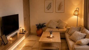 A modern living room with a flat-screen TV, a sofa, a coffee table, and a potted plant. - Elegant 2 Bedroom Apartment with Rooftop Terrace (Lemesos)