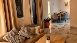 A living room with a sofa, a wooden coffee table, and a dining area with a table and chairs. - Elegant 2 Bedroom Apartment with Rooftop Terrace (Lemesos)