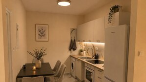 A compact kitchen with a dining area, a washing machine, and a refrigerator. - Elegant 2 Bedroom Apartment with Rooftop Terrace (Lemesos)