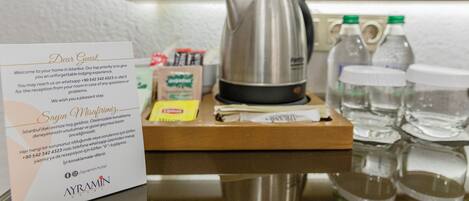 Ein Hotelrezeptionsbereich mit einer Willkommenskarte, einem Wasserkocher, Wasserflaschen und einer Kaffeemaschine auf der Theke.
