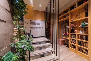 A modern interior with a staircase, a bookshelf, and a sign indicating the direction to the breakfast area. - Ayramin Deluxe Hotel Anex (İstanbul)