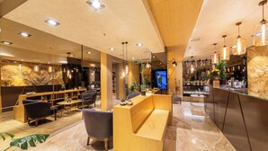 Un moderno vestíbulo de hotel con una recepción, zona de estar y un espejo grande.