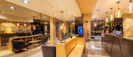 A modern hotel lobby with a reception desk, seating area, and a large mirror.